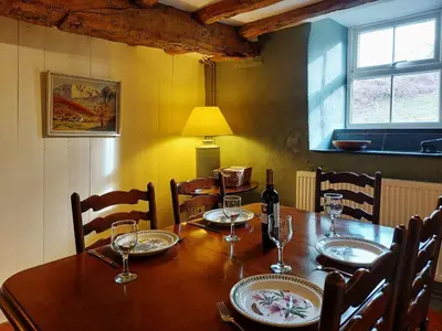a wooden table with chairs and a bottle of wine at Gallestra a Rustic, Rural Retreat Farm House Nr Dolgellau Snowdonia in Dolgellau