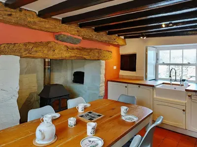 a kitchen with a wooden table with chairs and a fireplace at Gallestra a Rustic, Rural Retreat Farm House Nr Dolgellau Snowdonia in Dolgellau