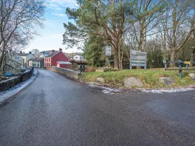 an empty road with a red house and trees at Yr Hen Efail in Abergorlech