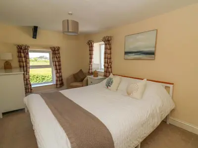 a bedroom with a large white bed and windows at Towyn Hall in New Quay