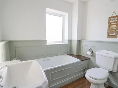 a bathroom with a tub and a toilet and a window at Towyn Hall in New Quay