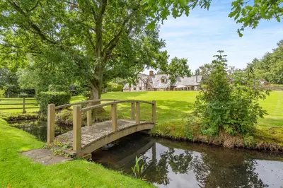 a bridge over a river in front of a house at Pultheley Cottage in Montgomery