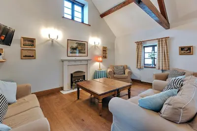 a living room with couches and a table and a fireplace at Finest Retreats - The Onibury in Onibury
