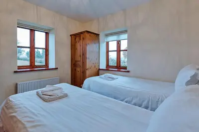 two beds in a room with two windows at Finest Retreats - The Onibury in Onibury