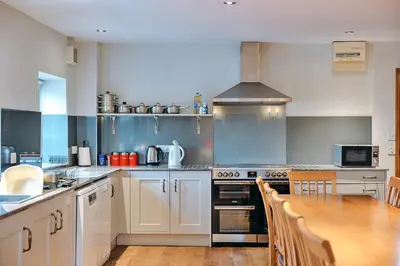 a kitchen with white cabinets and a wooden table at Finest Retreats - The Onibury in Onibury