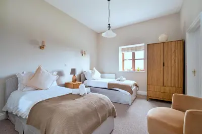 a bedroom with two beds and a chair and a window at Finest Retreats - The Park in Onibury