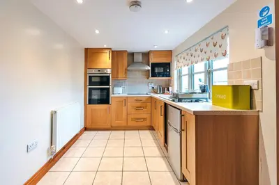 a large kitchen with wooden cabinets and appliances at Finest Retreats - Norton Cottage in Onibury