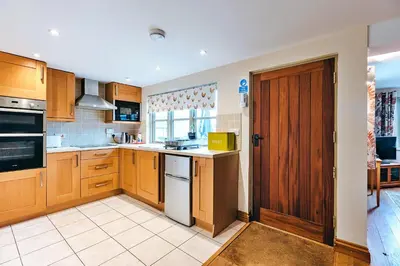 a large kitchen with wooden cabinets and a door at Finest Retreats - Norton Cottage in Onibury