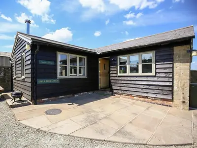 a black house with a patio in front of it at Finest Retreats - Norton Cottage in Onibury
