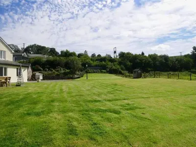 a large grassy yard with a house and trees at 4 Bed in Brecon oc-bn151 in Devynock