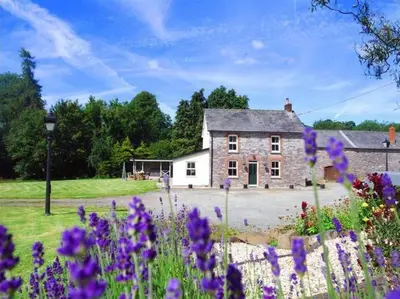 a stone house with purple flowers in front of it at 4 Bed in Brecon oc-bn151 in Devynock