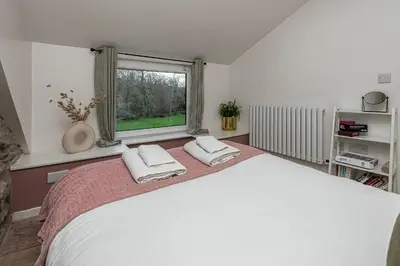 a bedroom with a large white bed and a window at Cheerful 2 bedroom cottage with garden in Llanelltyd