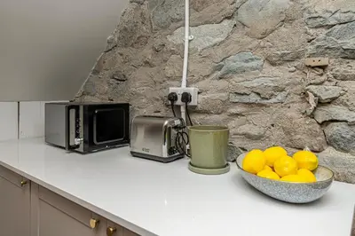 a kitchen counter with a bowl of oranges and a microwave at Cheerful 2 bedroom cottage with garden in Llanelltyd