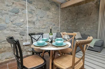 a table with chairs and a bottle of wine on a patio at Cheerful 2 bedroom cottage with garden in Llanelltyd