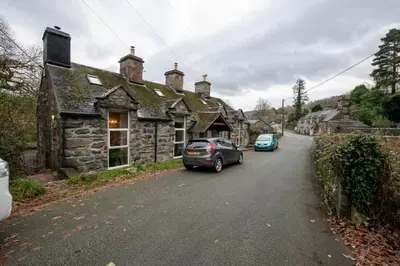 two cars parked in front of a stone house at Cheerful 2 bedroom cottage with garden in Llanelltyd