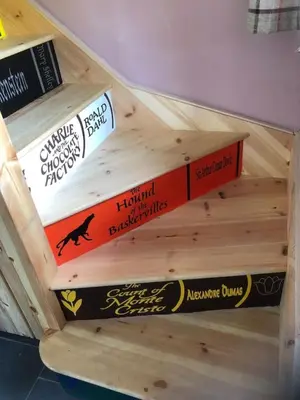a stack of books on a wooden shelf at Mwsogl - Luxurious Family Fishing Lodge Near Aberaeron With Private Fishing in Cross Inn