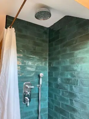 a shower in a bathroom with a green tiled wall at Rhedyn - Cosy Fishing Lodge Near Aberaeron in Cross Inn