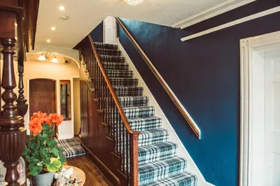 a staircase in a house with a blue wall at Penygelli Apartments in Newtown