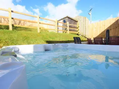 a hot tub in a backyard with a wooden fence at 5 Bed in Llanybydder oc-75907 in Llanwenog