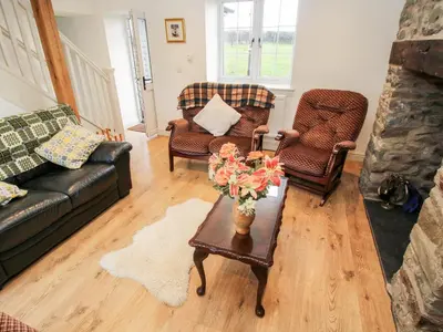 a living room with two couches and a table with flowers at Ty Gwyn in Welshpool