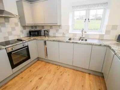 a kitchen with white cabinets and a wooden floor at Ty Gwyn in Welshpool
