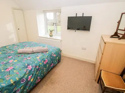 a bedroom with a bed and a tv on a wall at Ty Gwyn in Welshpool