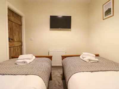 two beds in a room with a tv on the wall at Bwthyn Y Bugail in Blaenau-Ffestiniog