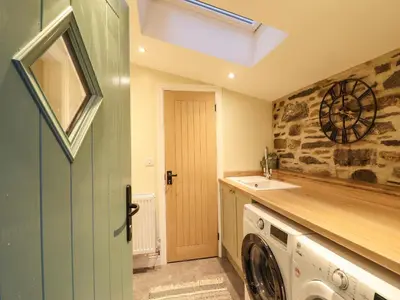 a laundry room with a washer and dryer and a clock at Bwthyn Y Bugail in Blaenau-Ffestiniog