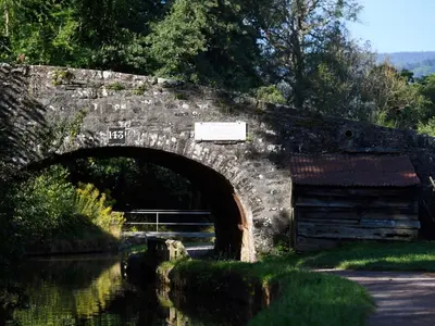 an old stone bridge over a river with a building at 1 Bed in Brecon oc-bn270 in Llansantffread
