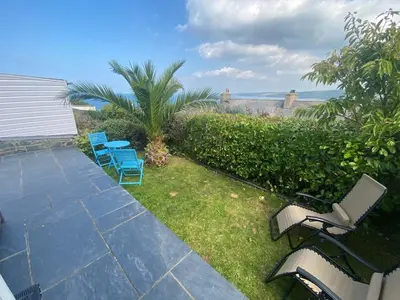 a group of chairs sitting on a patio with the ocean at Y Stabl in New Quay