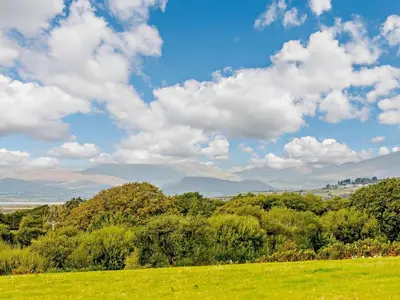a green field with trees and a sky with clouds at 2 Bed in Dyffryn Ardudwy oc-89438 in Dyffryn