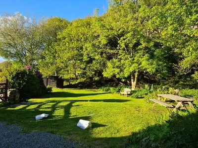 a park with a picnic table and a bench in the grass at Holiday Cottage in Snowdonia (Sleeps 10) in Harlech