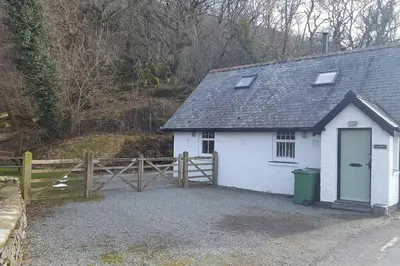 a small white building with a gate and a fence at Holiday Cottage in Snowdonia (Sleeps 10) in Harlech