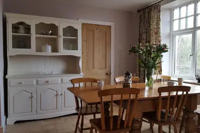 a dining room with a table and a cabinet at Holiday Cottage in Snowdonia (Sleeps 10) in Harlech
