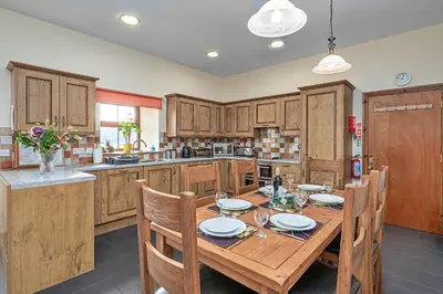 a kitchen with wooden cabinets and a wooden table with chairs at Finest Retreats - Eithinog in Talybont