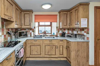 a kitchen with wooden cabinets and a sink at Finest Retreats - Helygen in Talybont