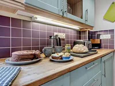 a kitchen with a table with a cake on a counter at 3 Bed in Carmarthen oc-92116 in Rhyd-cymmerau
