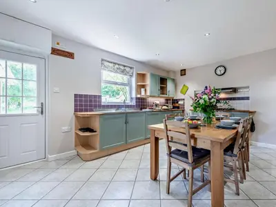 a kitchen with a wooden table with chairs and a table sidx sidx sidx at 3 Bed in Carmarthen oc-92116 in Rhyd-cymmerau