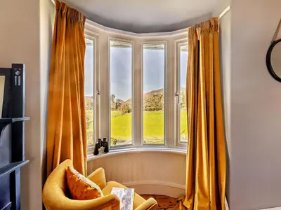 a room with a large window with yellow curtains at 4 Bed in Friog 42772 in Fairbourne