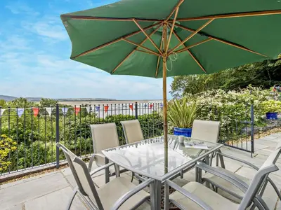 a table and chairs with a green umbrella at 3 Bed in Aberdovey DY032 in Aberdyfi