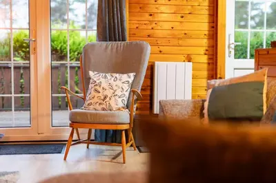 a chair with a pillow on it in a living room at Rural Log Cabin in Snowdonia near Coed y Brenin by Seren Short Stays in Ffestiniog