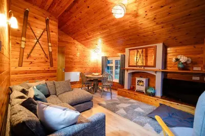 a living room with a couch and a fireplace at Rural Log Cabin in Snowdonia near Coed y Brenin by Seren Short Stays in Ffestiniog
