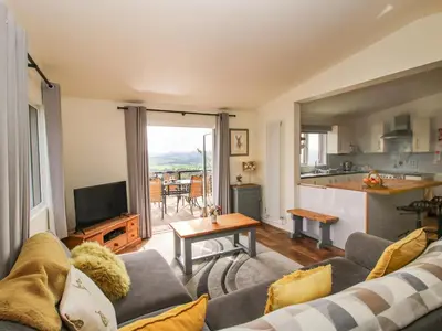 a living room with a couch and a kitchen at Dragonfly Lodge in Shrewsbury