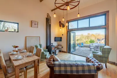 a living room with a table and a large window at Outshot Barn in Hay-on-Wye