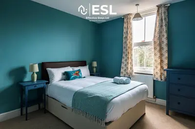 a blue bedroom with a bed and a window at 4 Bedroom House. Close to Shrewsbury Town Centre in Shrewsbury