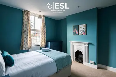 a bedroom with blue walls and a bed with a fireplace at 4 Bedroom House. Close to Shrewsbury Town Centre in Shrewsbury