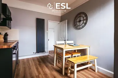 a kitchen with a table and a clock on the wall at 4 Bedroom House. Close to Shrewsbury Town Centre in Shrewsbury