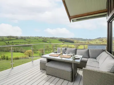 a patio with a couch and a table on a deck at Barcud Coch - Red Kite in Welshpool