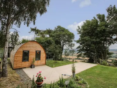 a small wooden cabin in a garden with trees at The Pod in Shrewsbury