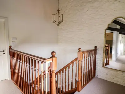 a hallway with a wooden staircase and a mirror at Dant Y Llew in Bow Street